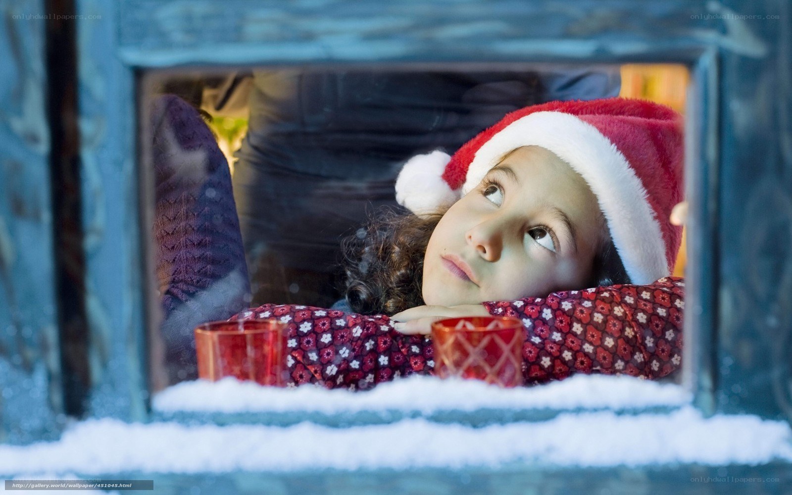 child in santa hat at window