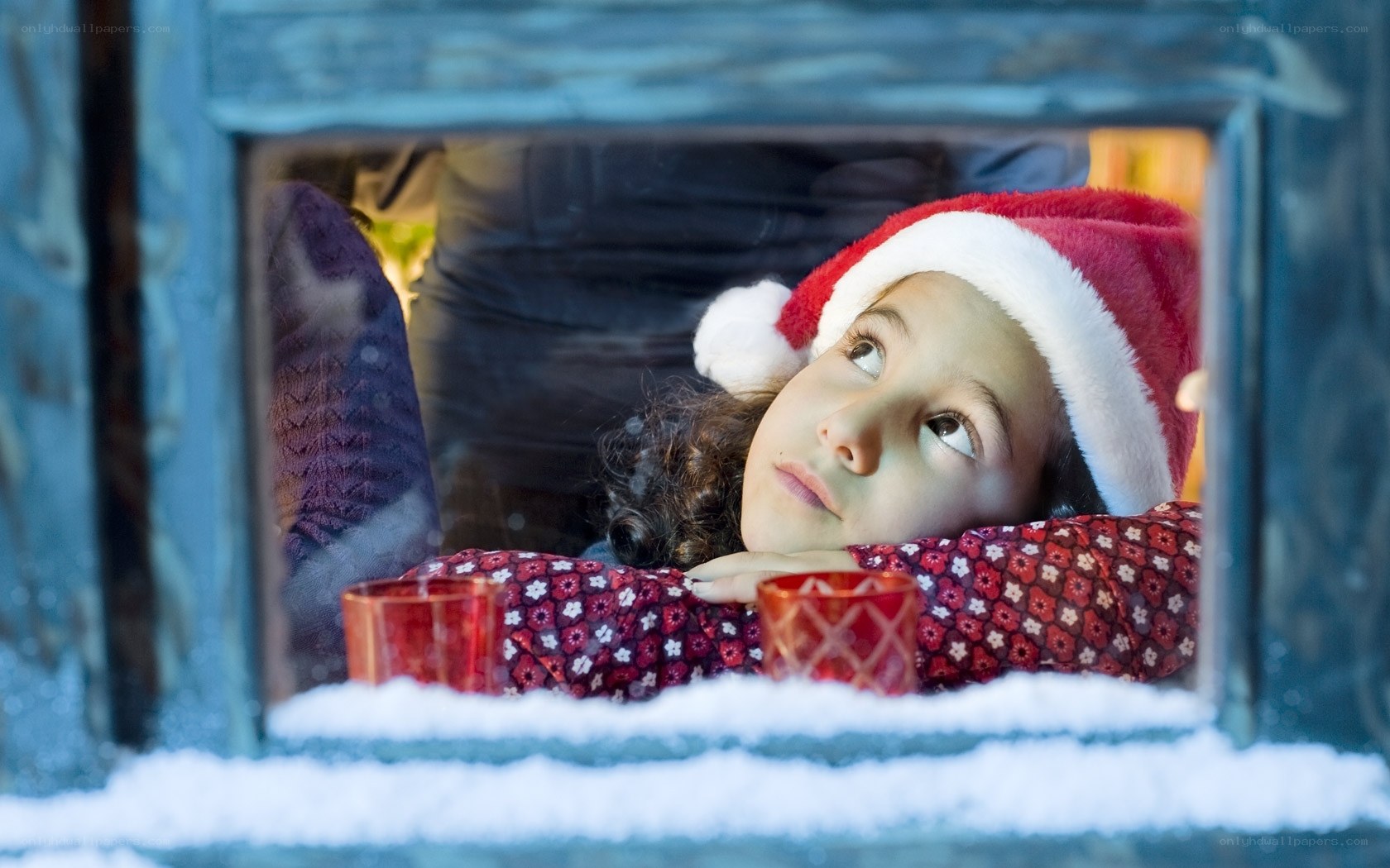 child in santa hat at window