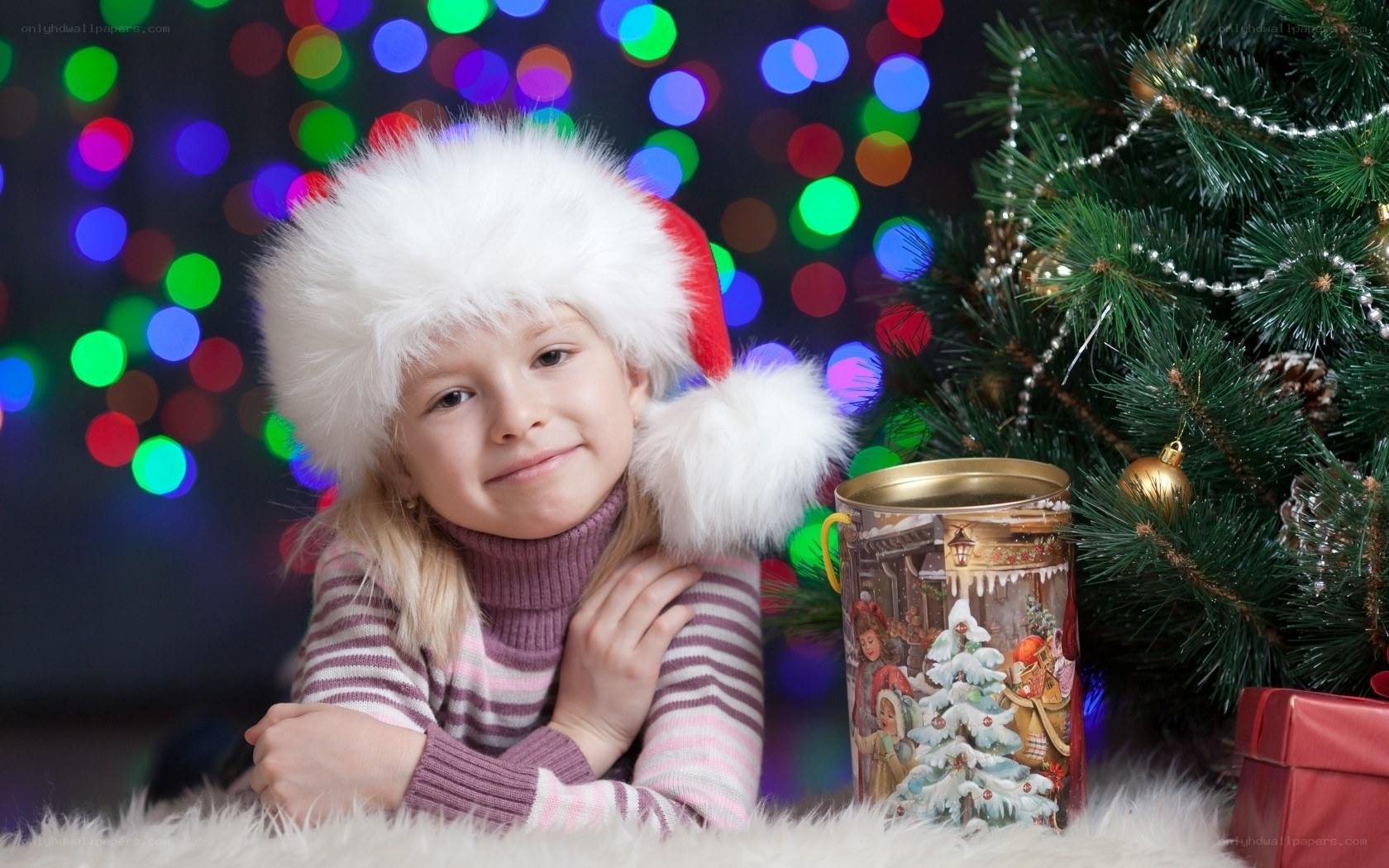 child in santa hat by christmas tree