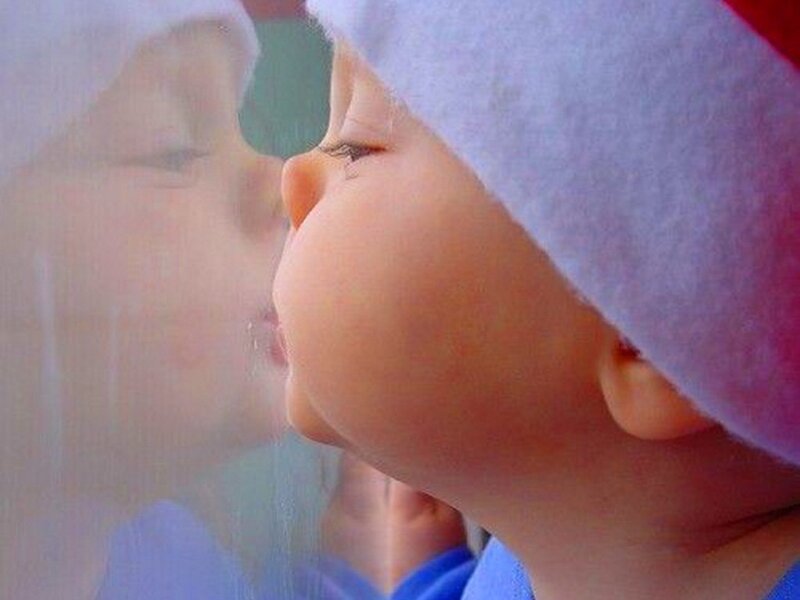 child in santa hat looking out window