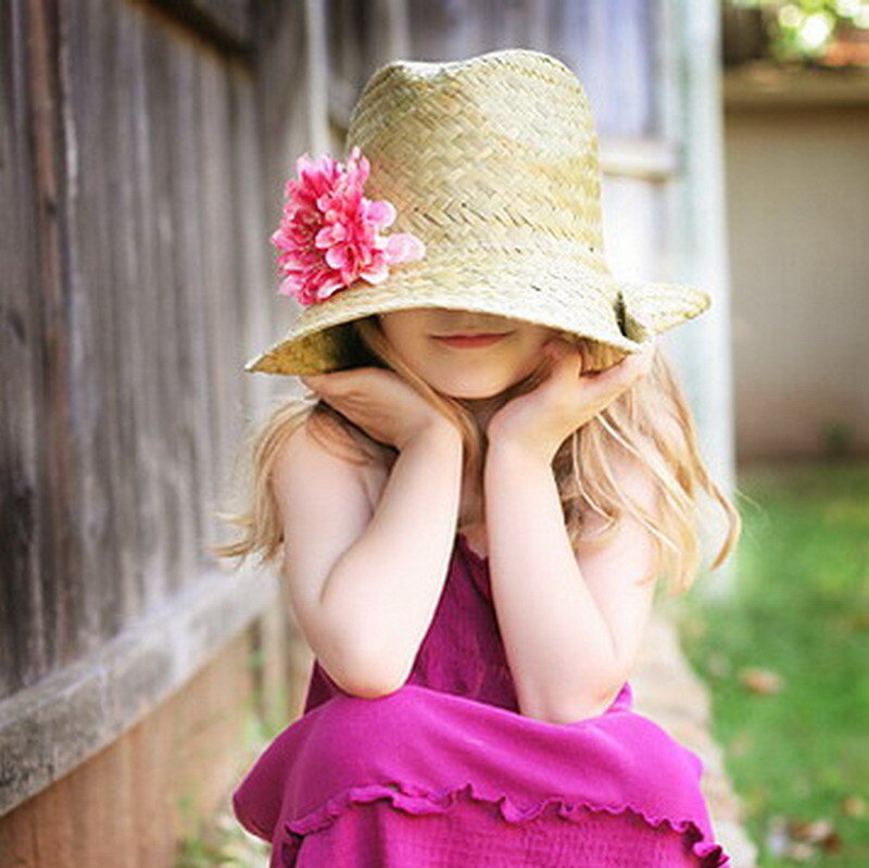 child in straw hat with flower