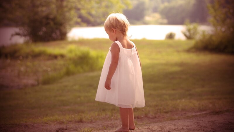 child in white dress by lake