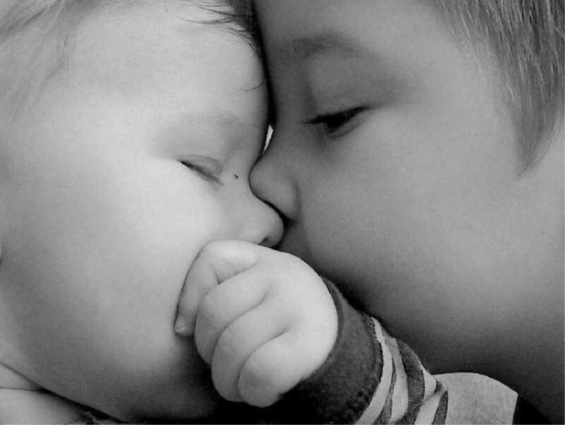 child kissing baby's forehead