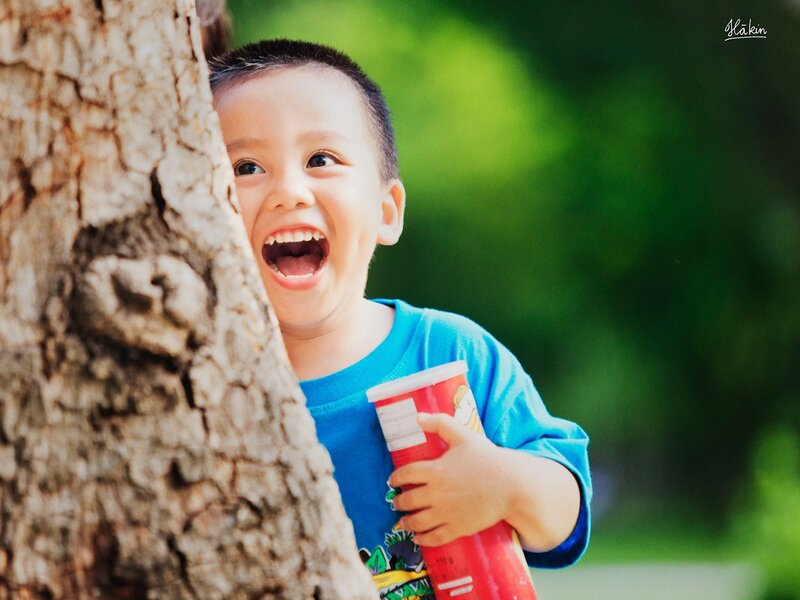child laughing behind tree