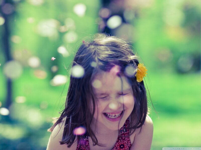 child laughing with dandelion