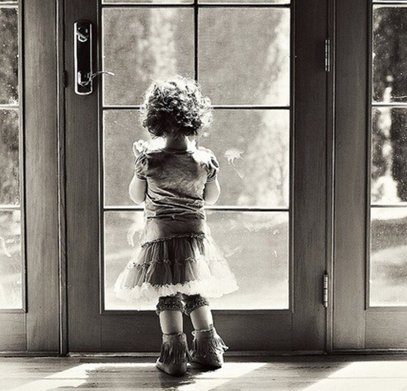 Child Looking Through Glass Door