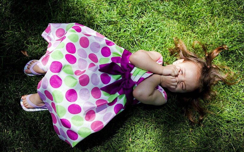 child lying on grass laughing