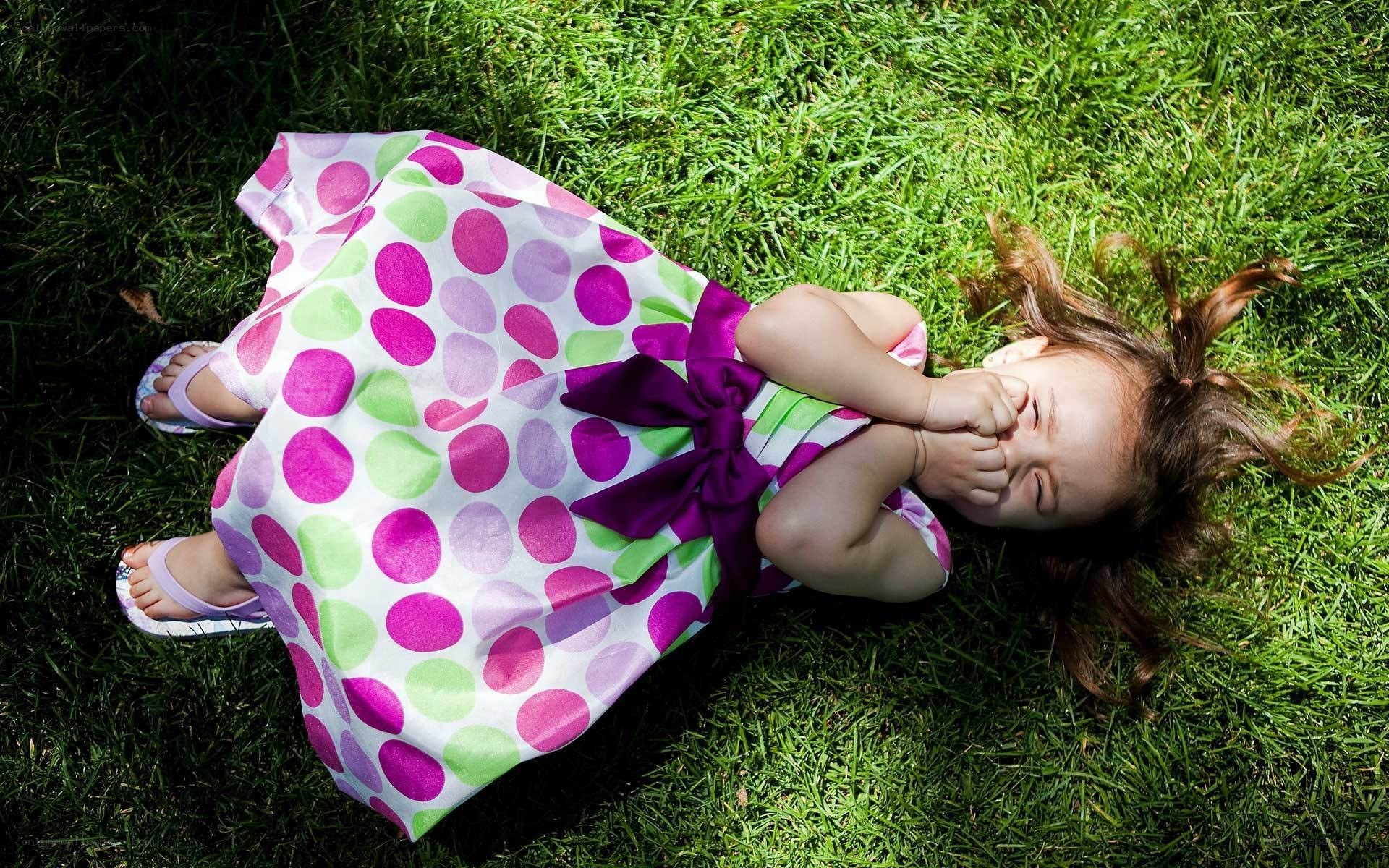 child lying on grass laughing