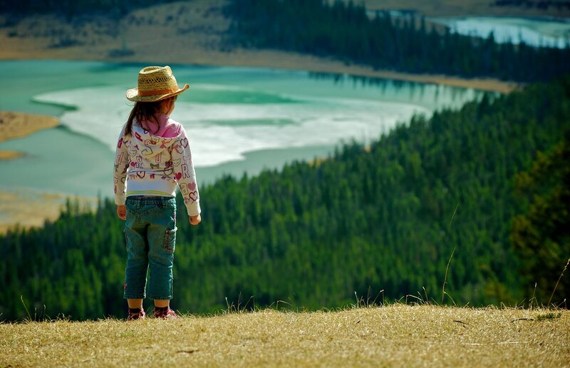 Child on a hill overlooking a lake