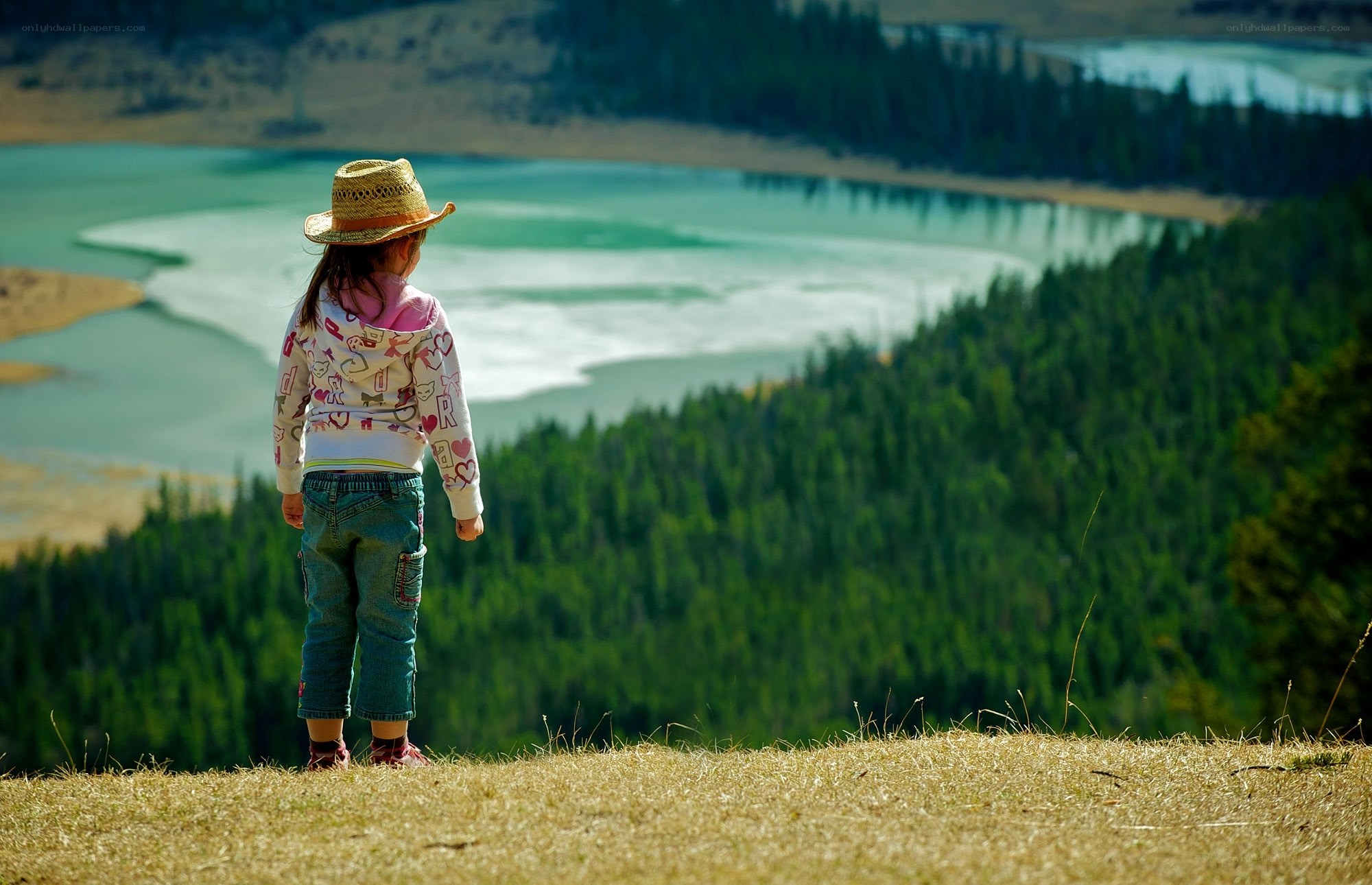 Child on a hill overlooking a lake