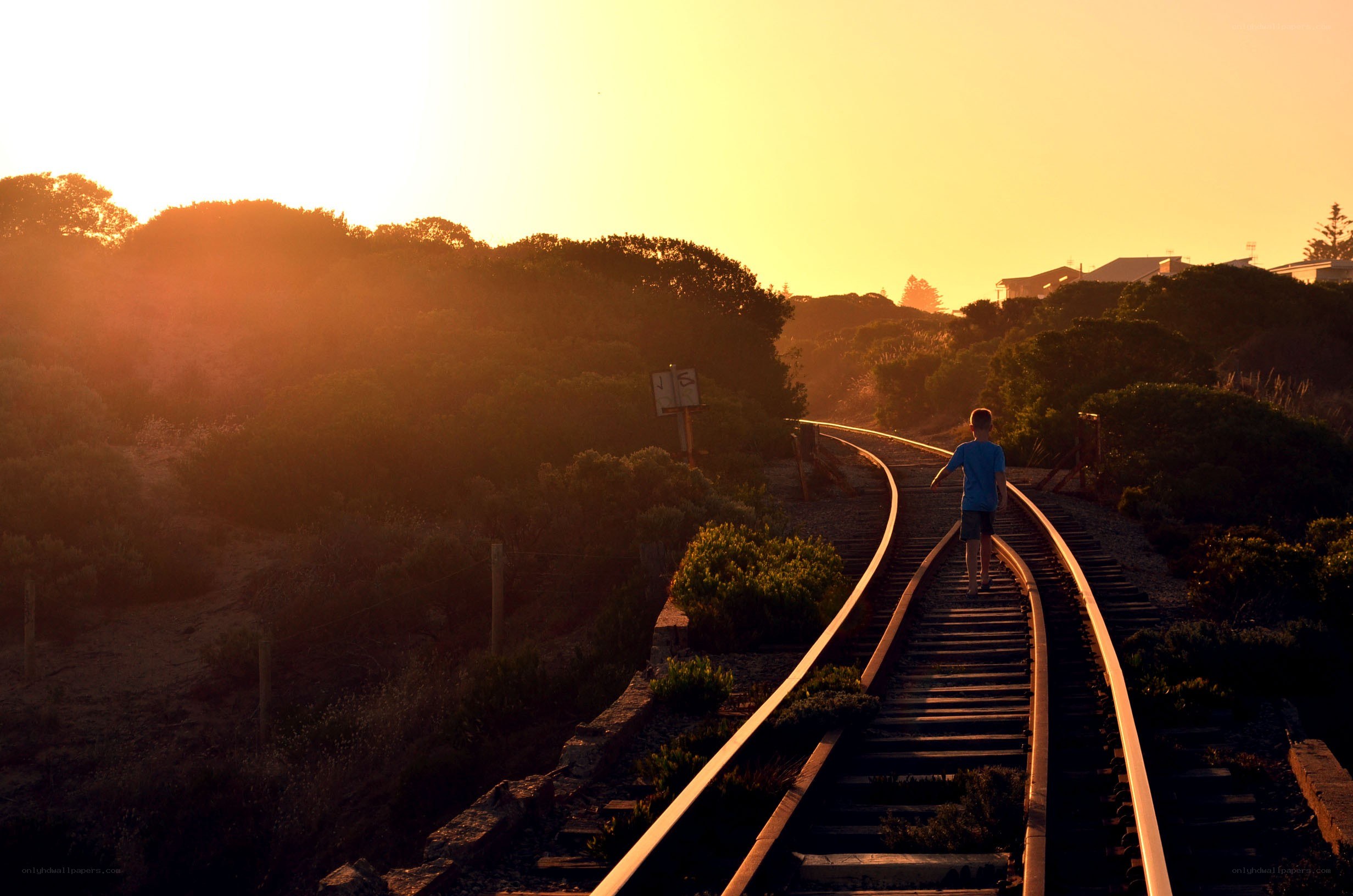 Child on train tracks at sunset