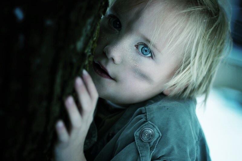 child peeking from behind tree