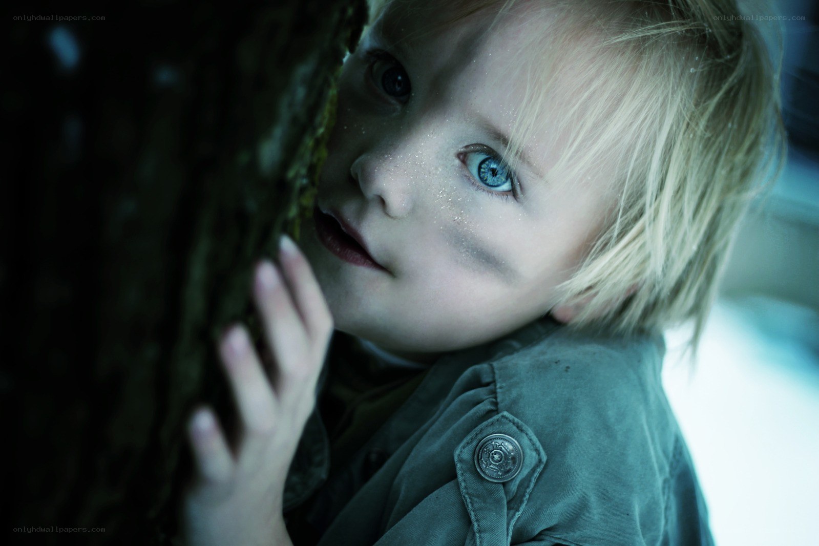 child peeking from behind tree
