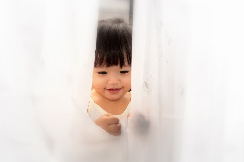 Child Peeking Through Curtain