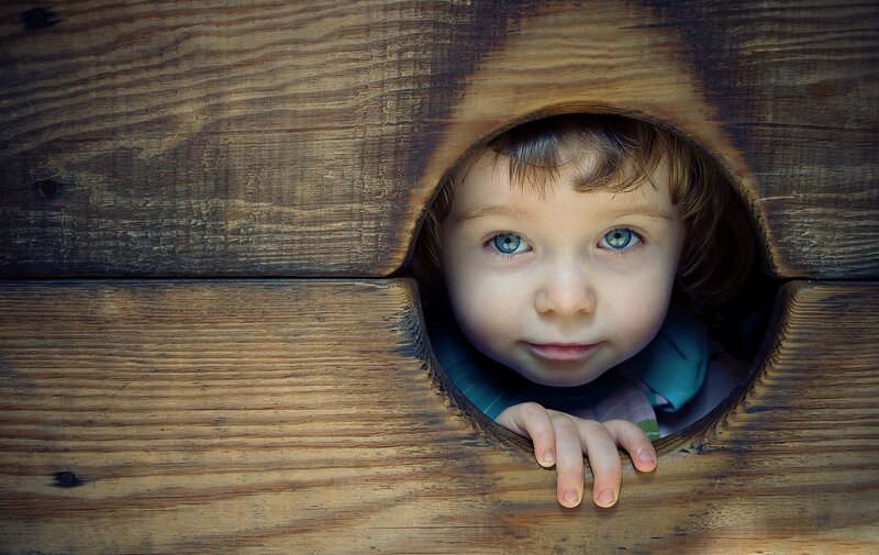 Child Peeking Through Hole — Brown