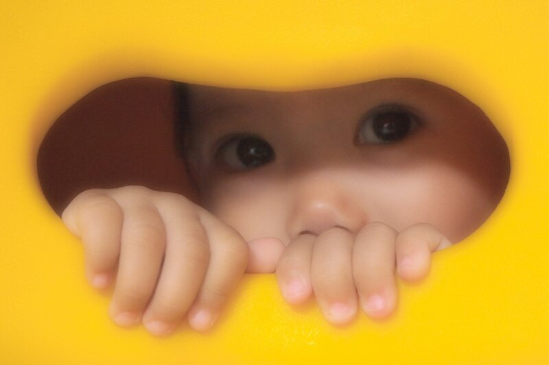 Child Peeking Through Hole — Yellow