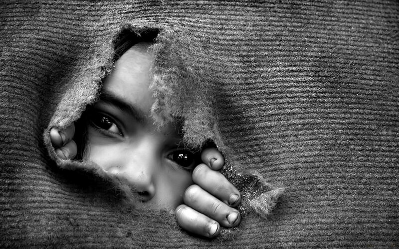 child peeking through torn fabric