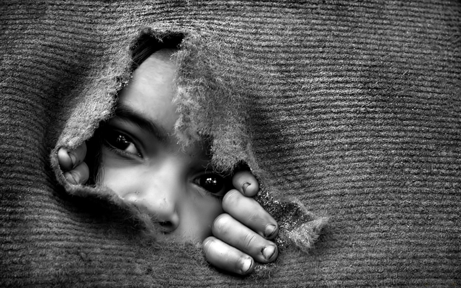child peeking through torn fabric