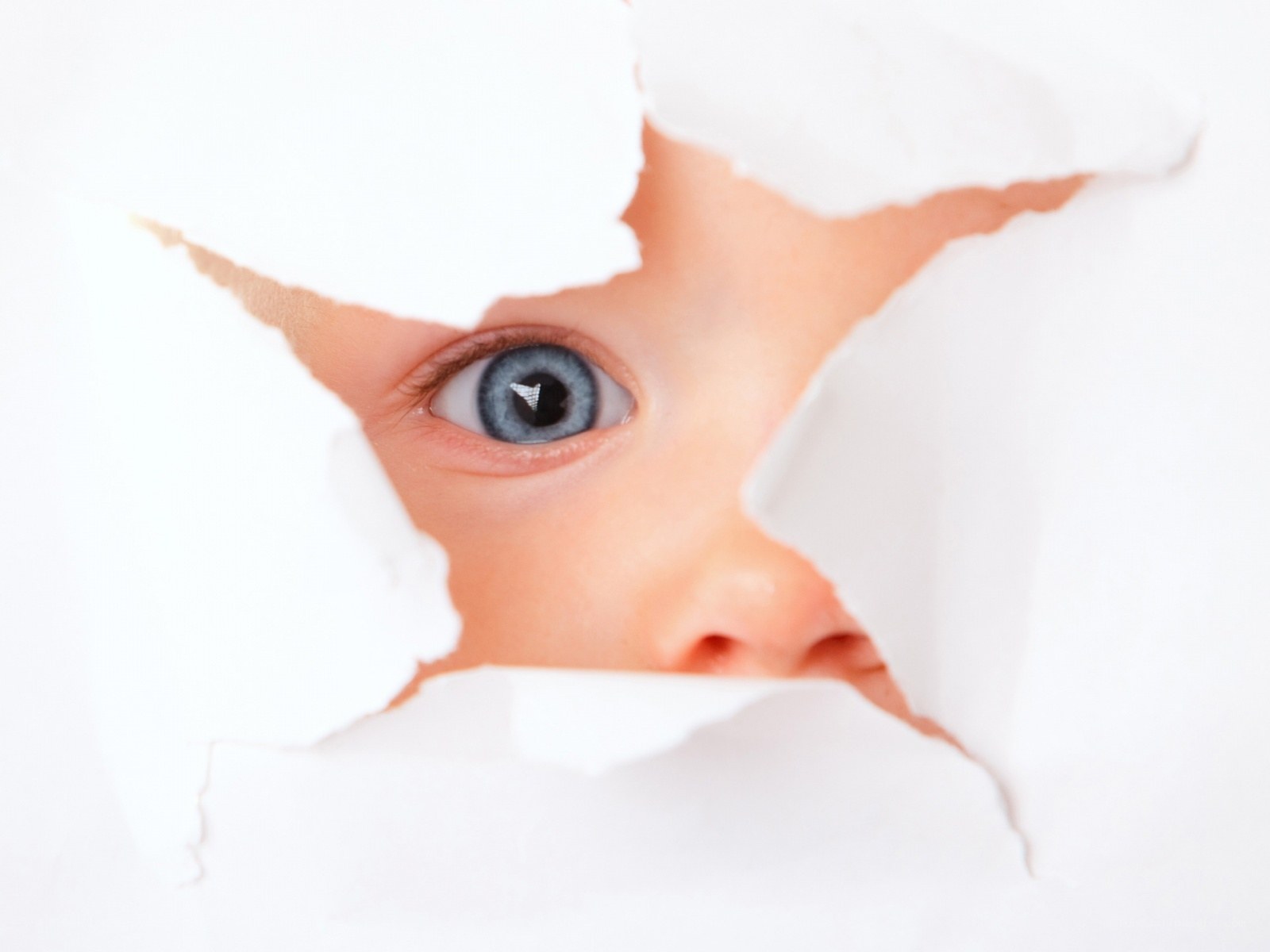 child peeking through torn paper