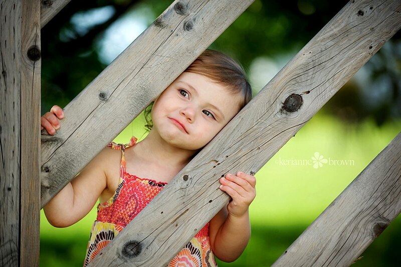 child peeking through wooden fence