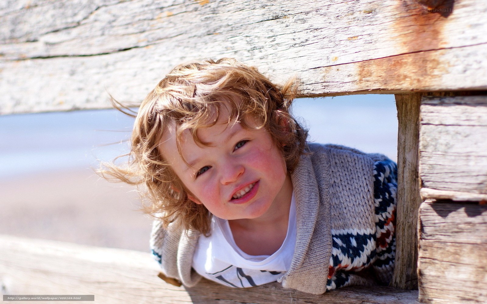 child peeking through wooden structure