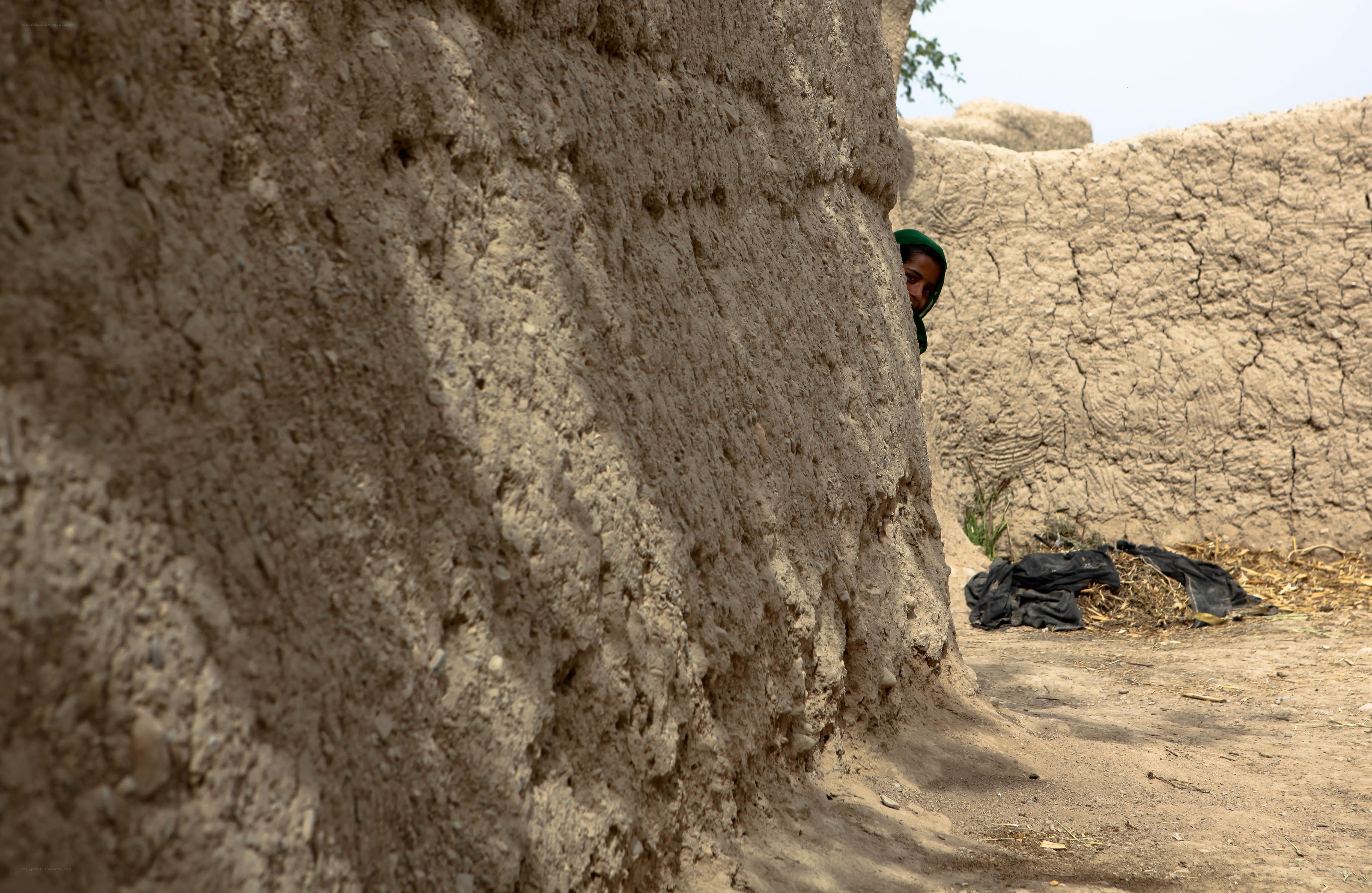 Child peering from behind a wall