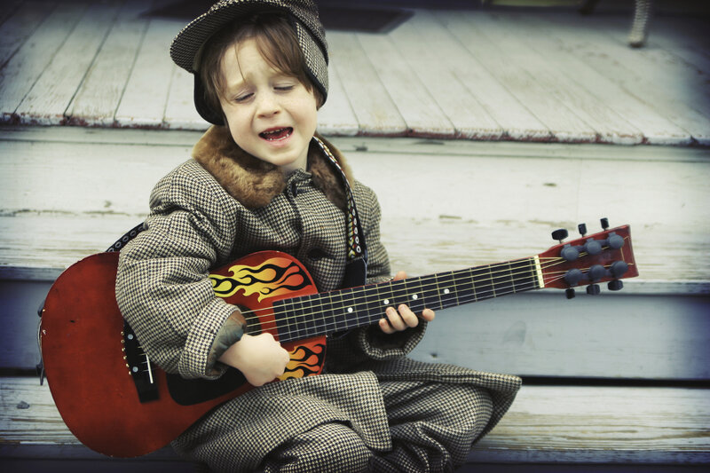 child playing guitar on porch