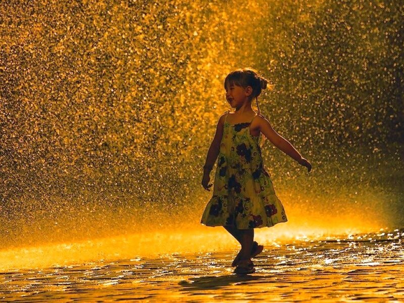 child playing in golden water spray