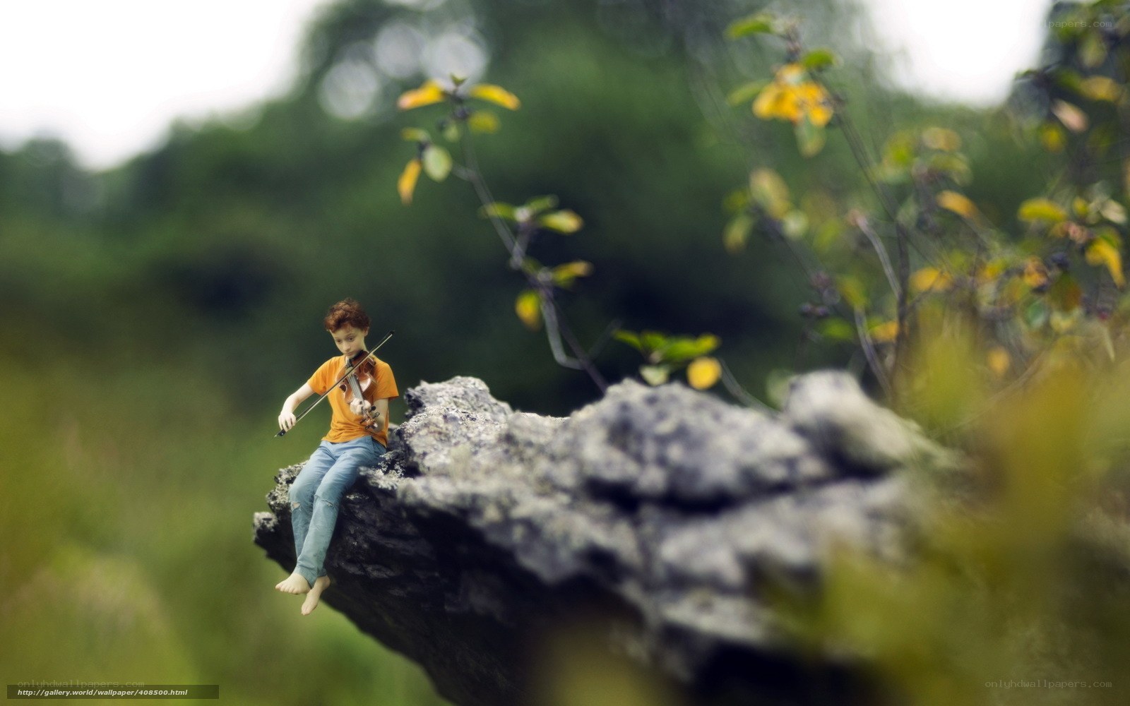 Child playing violin on rock