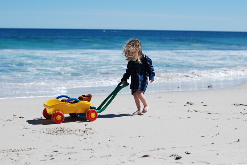 child playing with toy car on beach