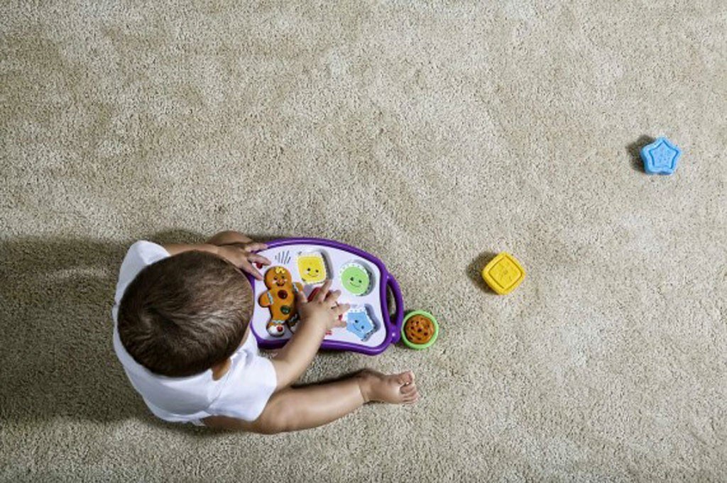 child playing with toy on carpet