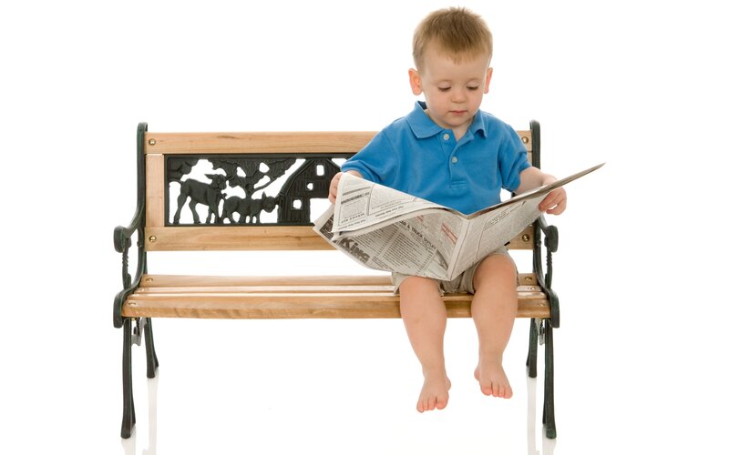 child reading newspaper on bench