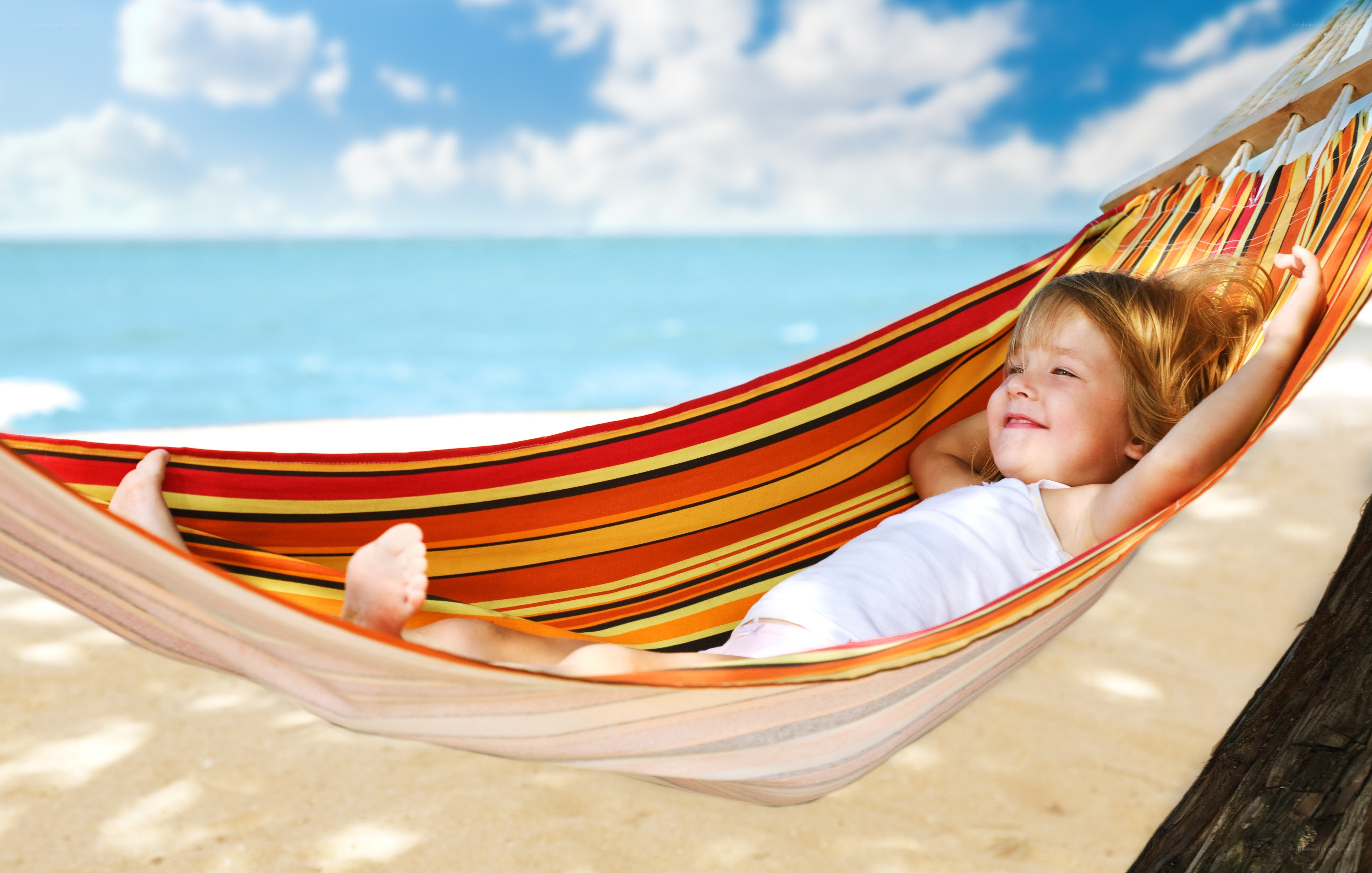 Child relaxing in hammock on beach