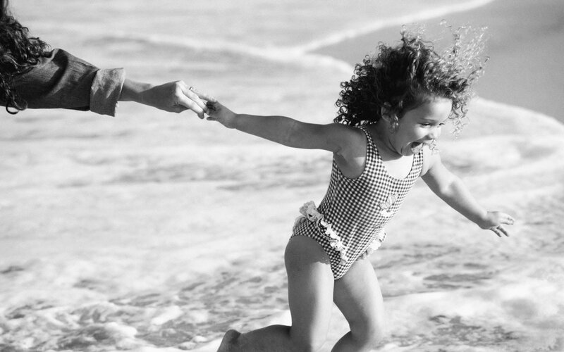 child running on beach with adult