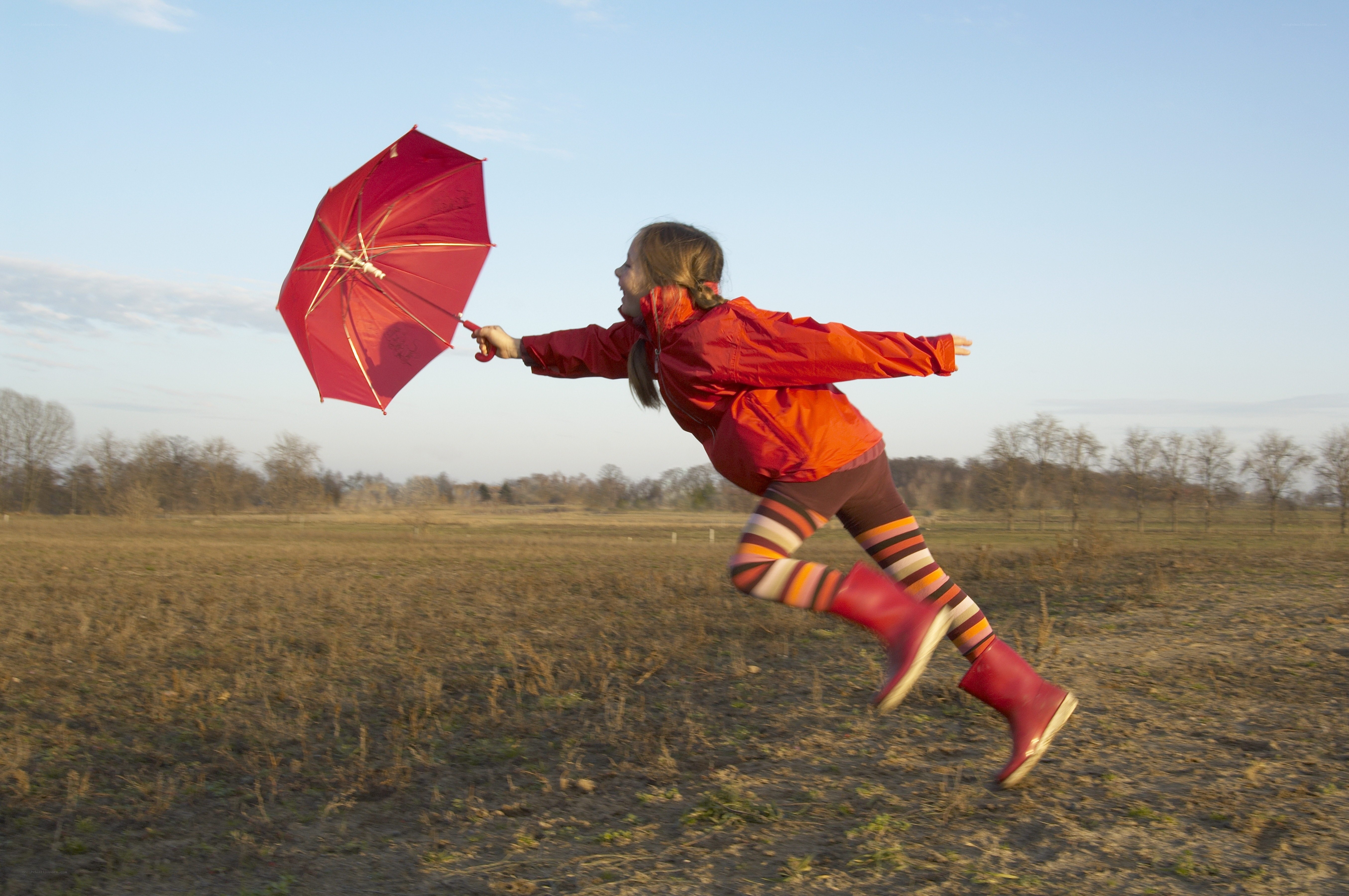 child running with red umbrella