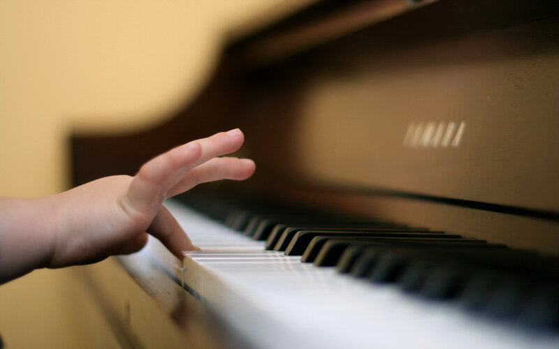 Child's Hand on Piano Keys — Brown