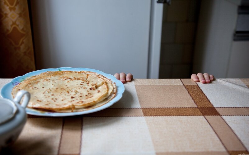 child's hands on table with pancakes