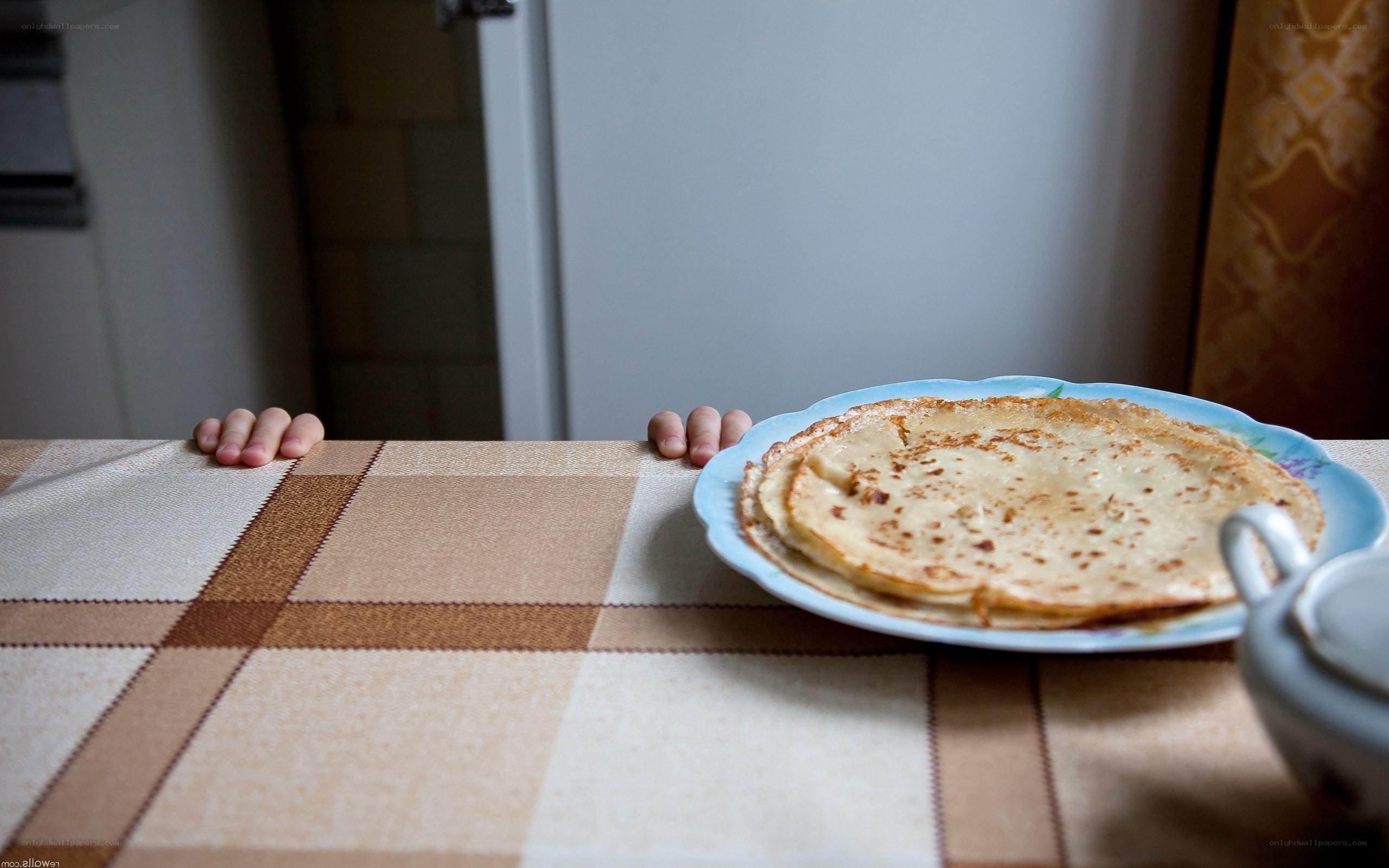 Child's hands on table with pancakes