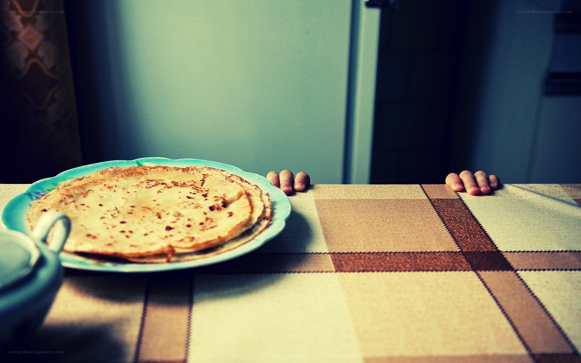 Child's hands on table with pancakes