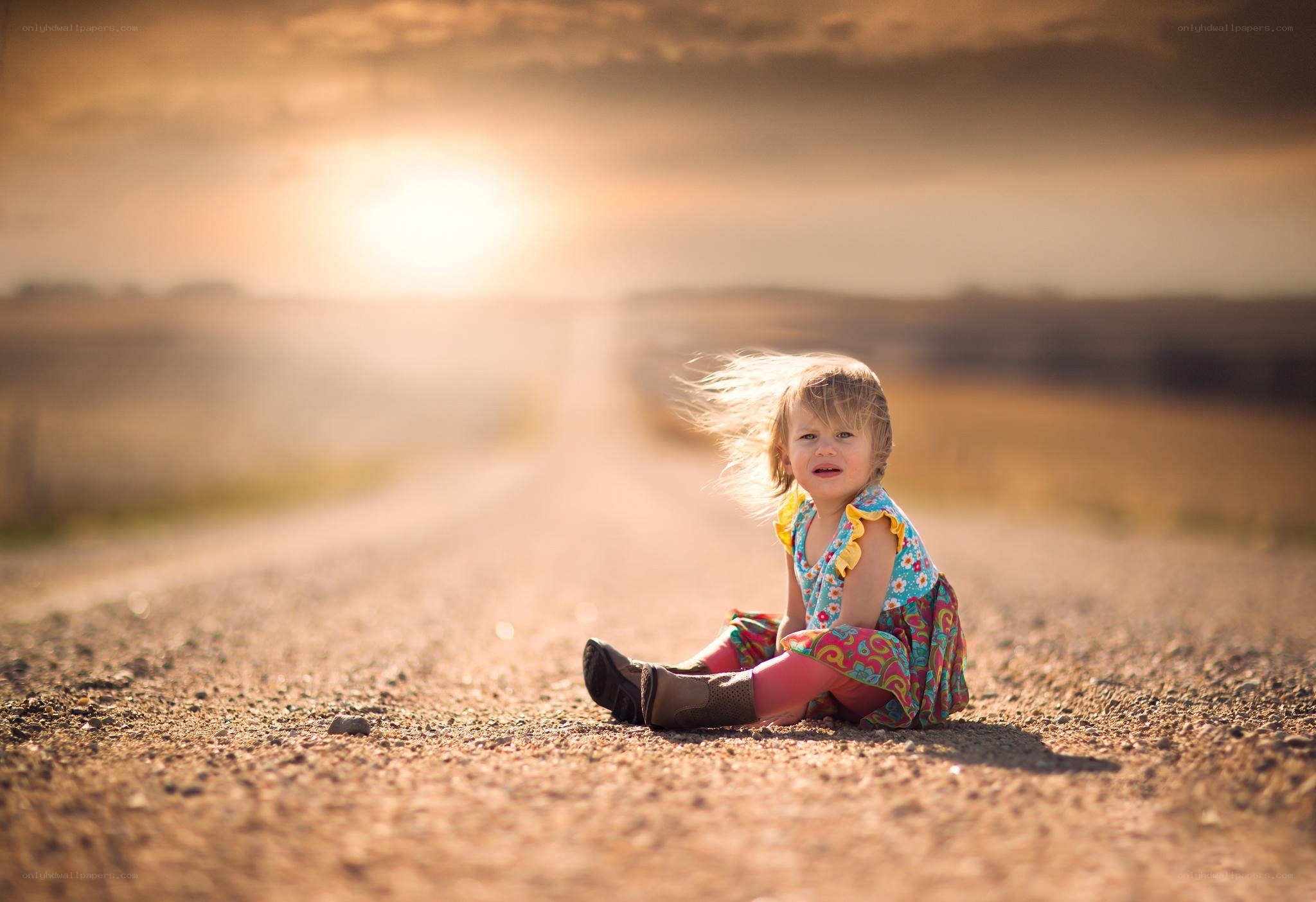 child sitting on a dirt road
