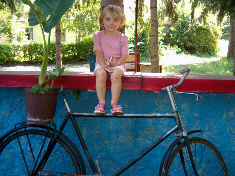 child sitting on a wall with bicycle