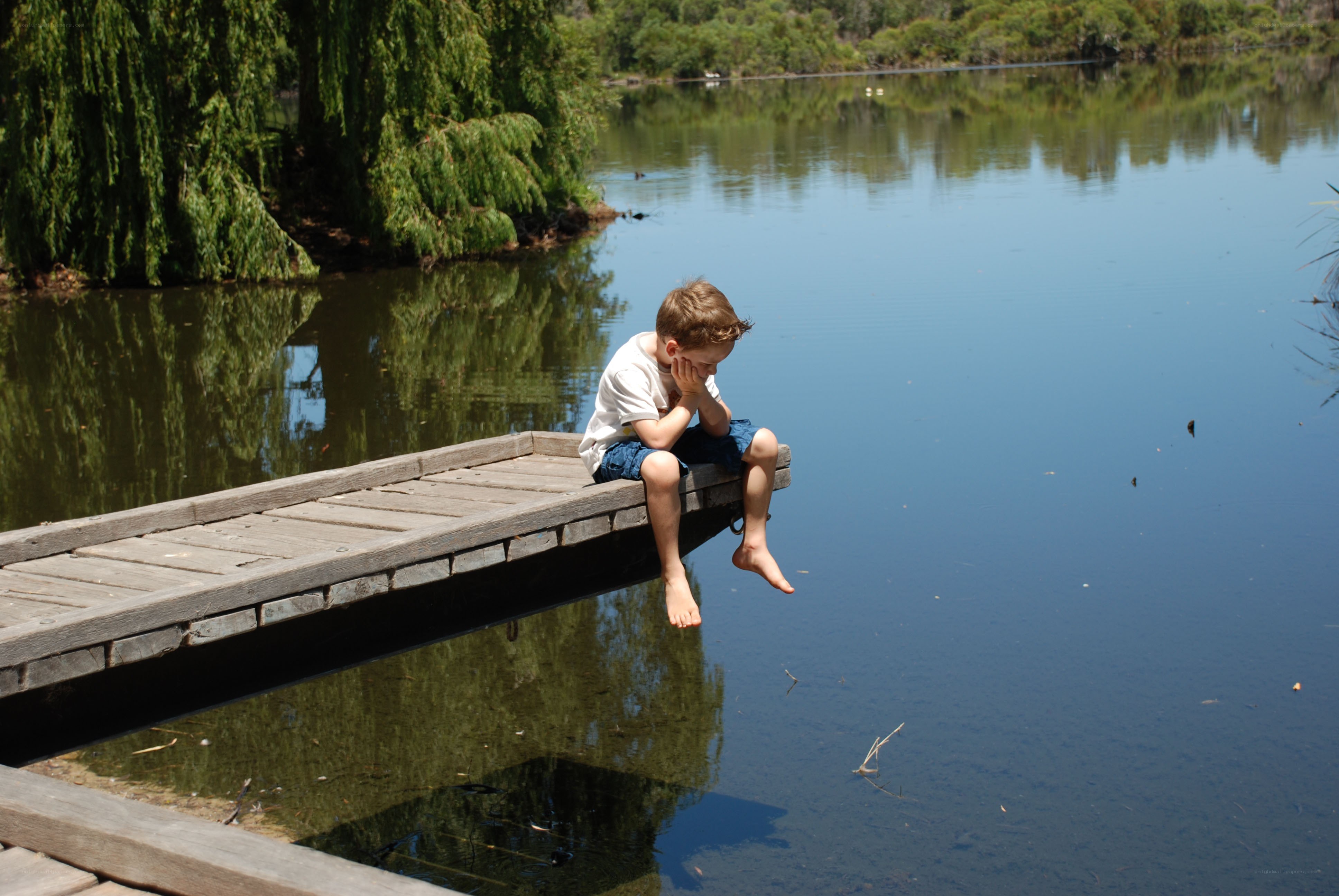 child sitting on dock by lake