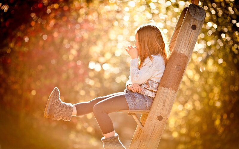 child sitting on ladder in autumn