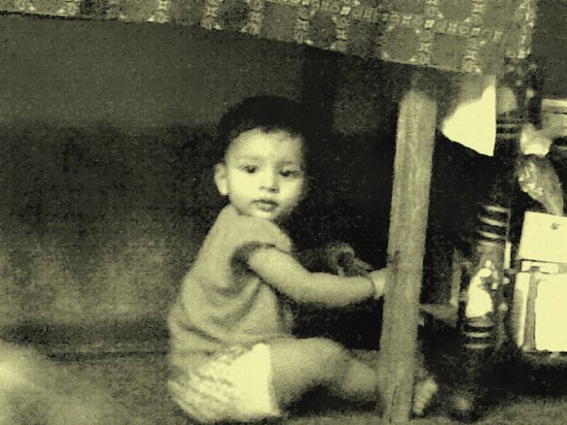 child sitting under a table