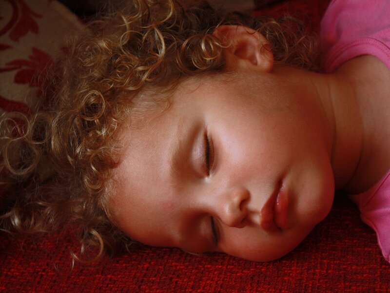 Child Sleeping on Red Surface