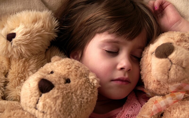 child sleeping with teddy bears