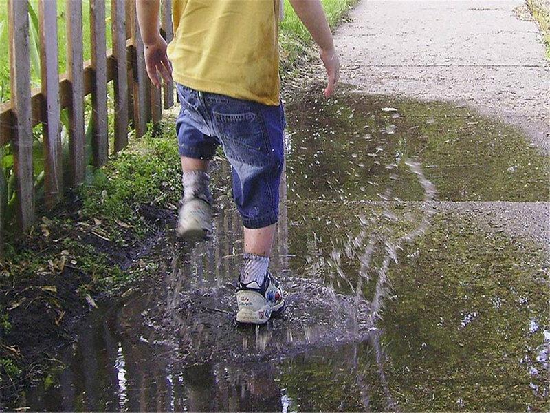 child splashing in a puddle