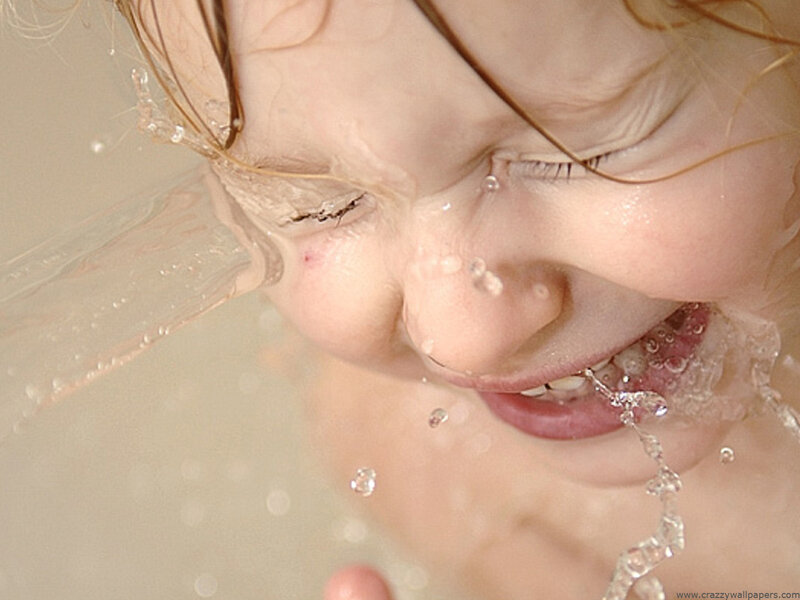 child splashing water in bathtub