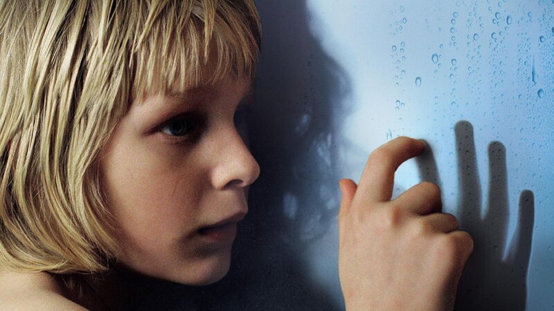 child touching rain-covered glass
