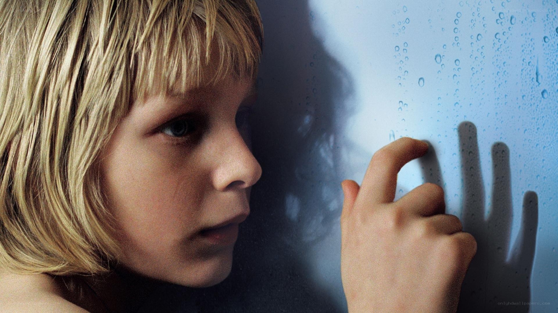 child touching rain-covered glass